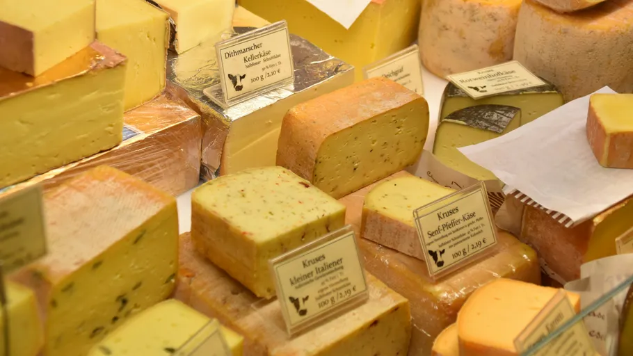 Various cheeses displayed with labels in a shop.