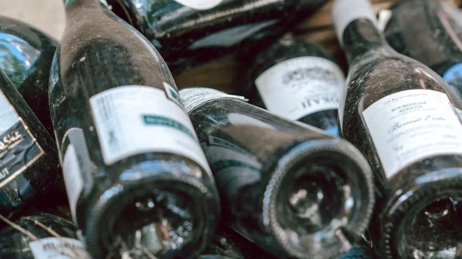 Dusty wine bottles lying on wooden surface.