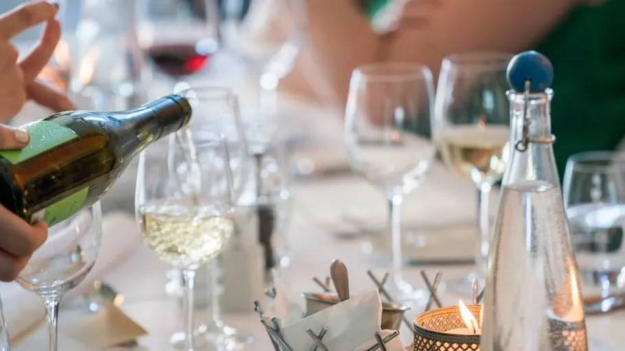 Wein wird in Glas am eleganten Tisch eingeschenkt.