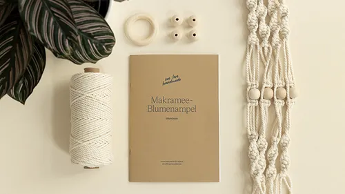 Makramee-Set mit Heft auf Tisch.