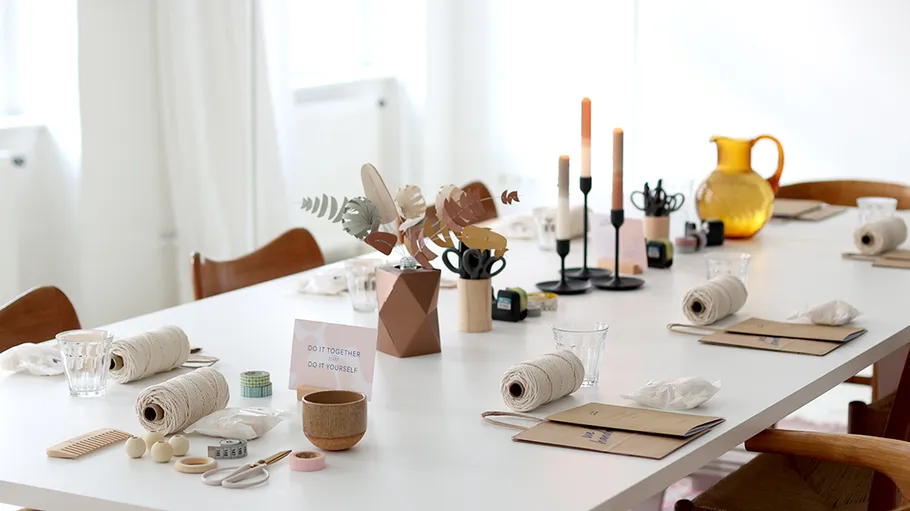 Craft table set with DIY materials, candles, decor.