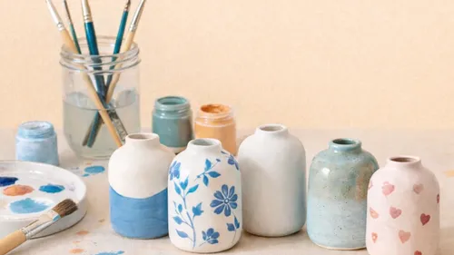 Painted vases with brushes and jars in background.