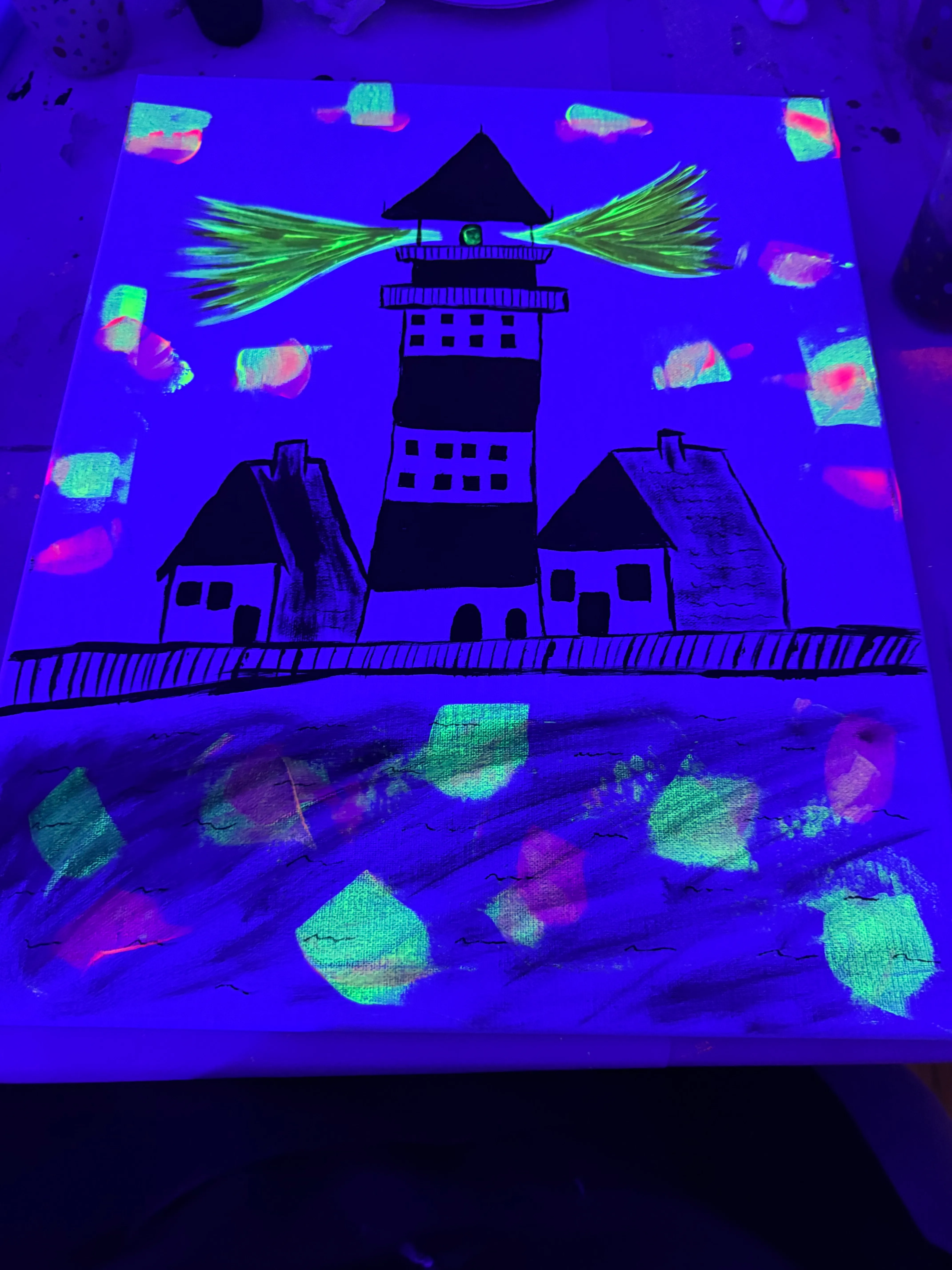 Leuchtturm und Häuser leuchten unter Schwarzlicht.