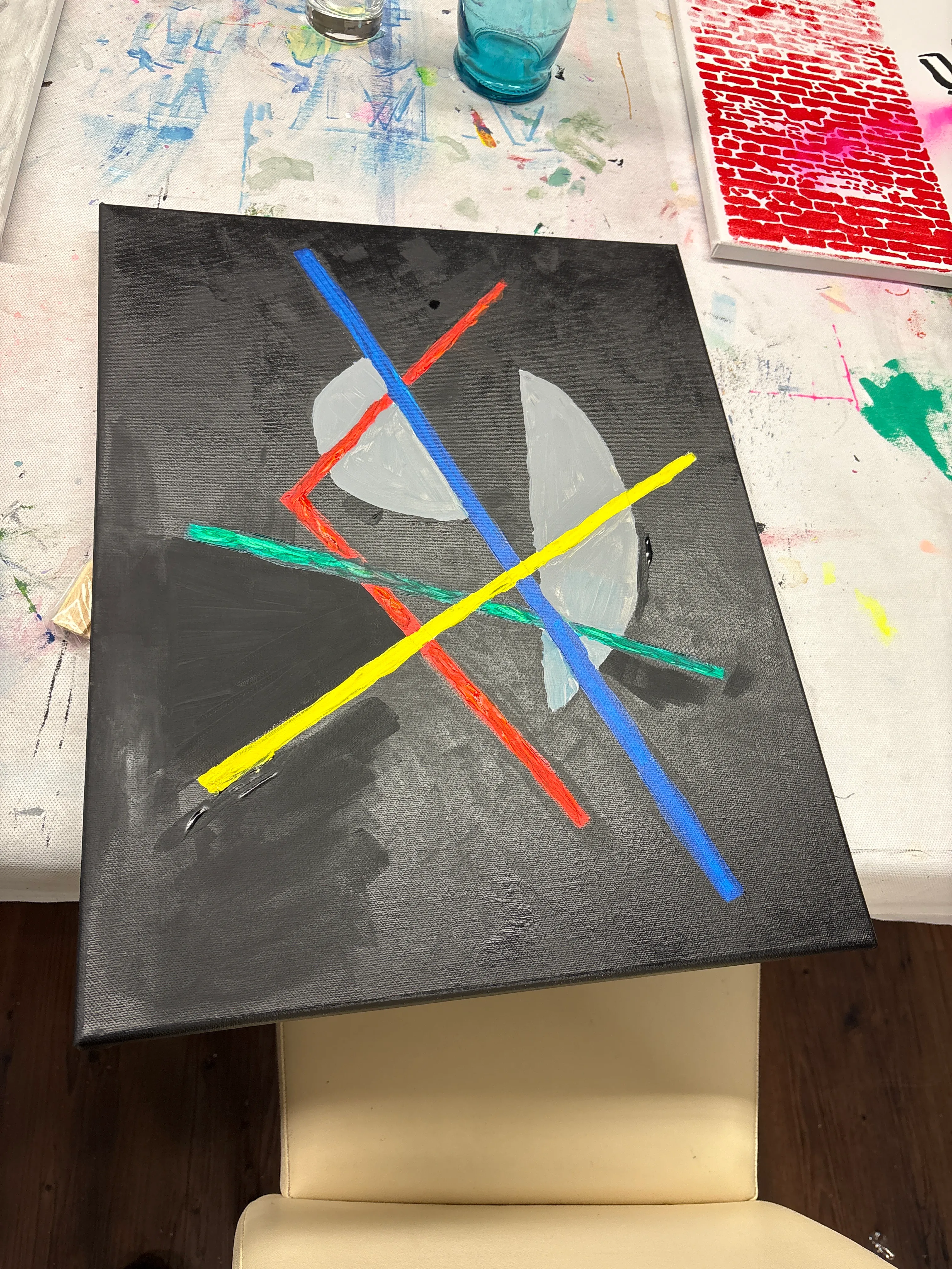 Abstraktes Gemälde mit farbigen Linien auf Tisch.