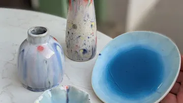 Bunte Keramikvasen und Schale auf Tisch.