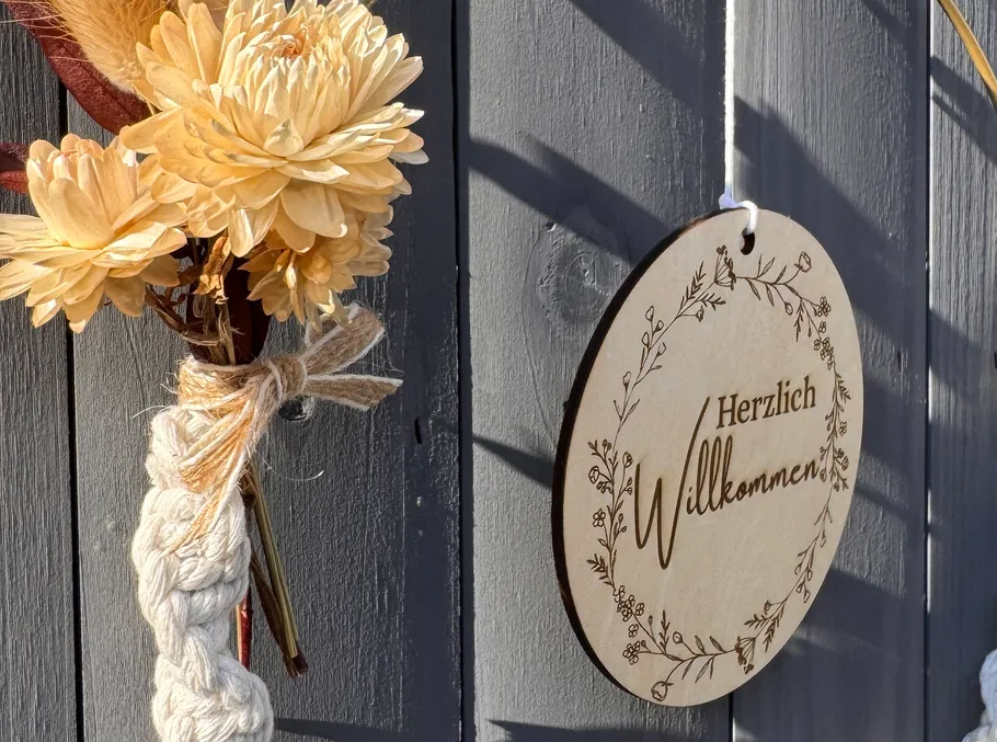 Flowers and a welcome sign on a wooden wall.