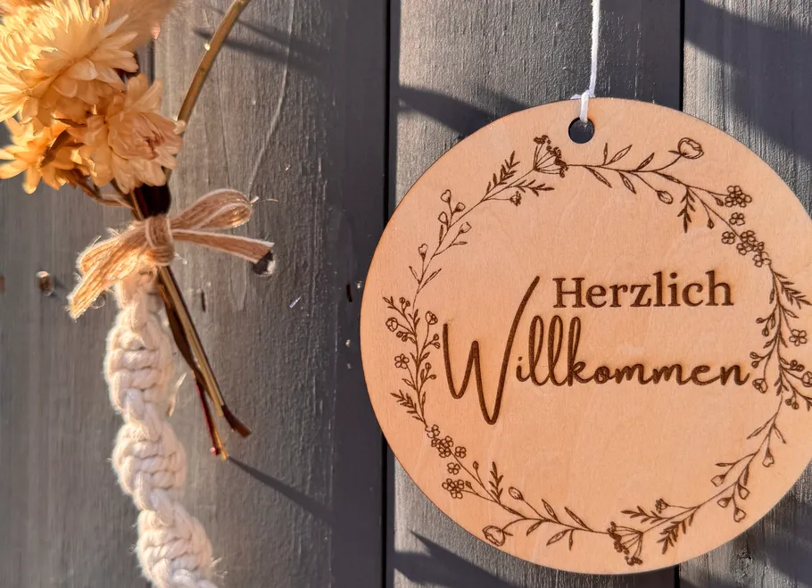 Wooden welcome sign on a gray door.