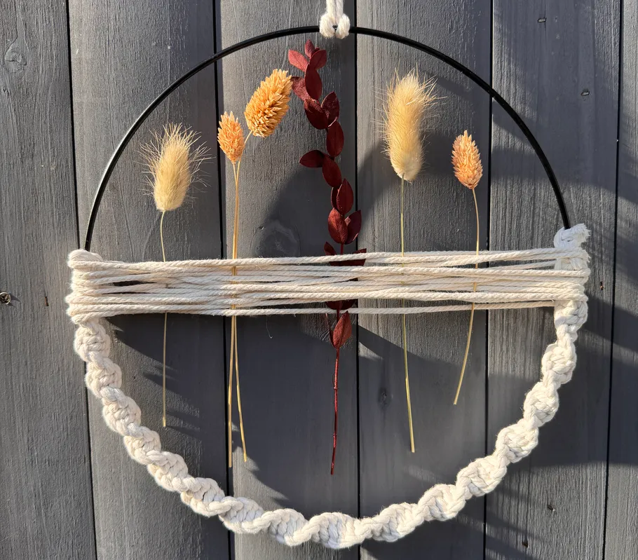 Gewebter Wandschmuck mit getrockneten Blumen und Blättern.