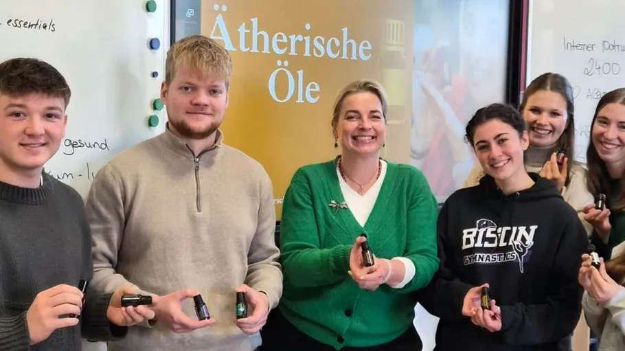 Sechs Personen halten Flaschen im Klassenzimmer.