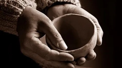 Hands holding a clay bowl, close-up shot.