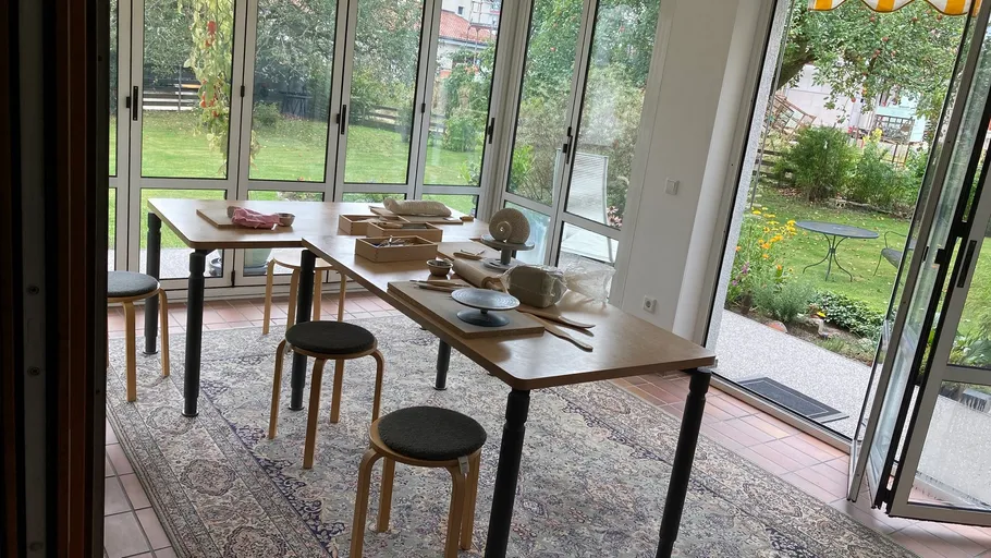 Tische mit Töpferwerkzeugen in hellem Raum.