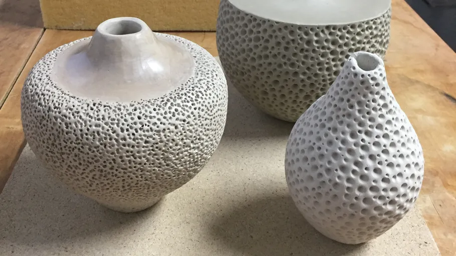 Textured ceramic vases on a wooden surface.