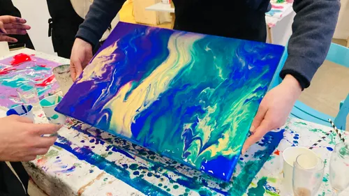 Abstract painting held by two people in class.