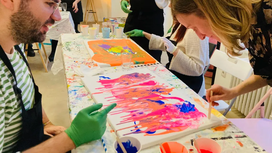 People painting abstract art on canvases indoors.