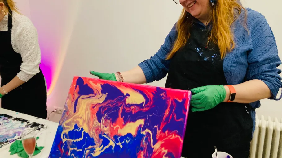 Woman holding a colorful abstract painting indoors.