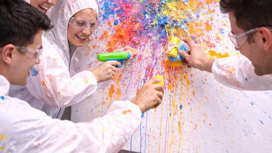 Menschen spritzen Farbe auf Leinwand, Schutzkleidung tragend.