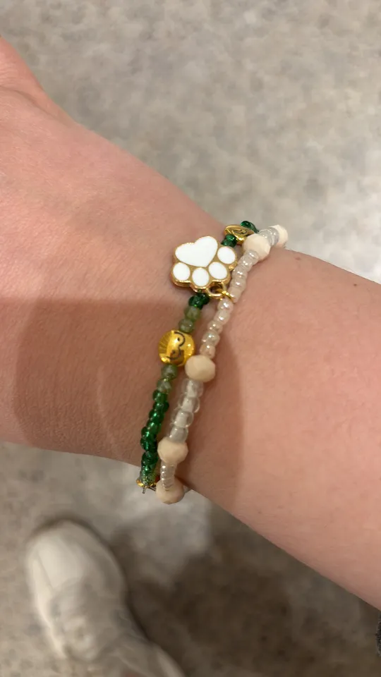 Bracelets with charms on wrist, blurred background.