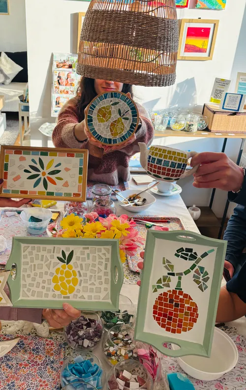 Personen zeigen Mosaikkunst in einem gemütlichen Raum.