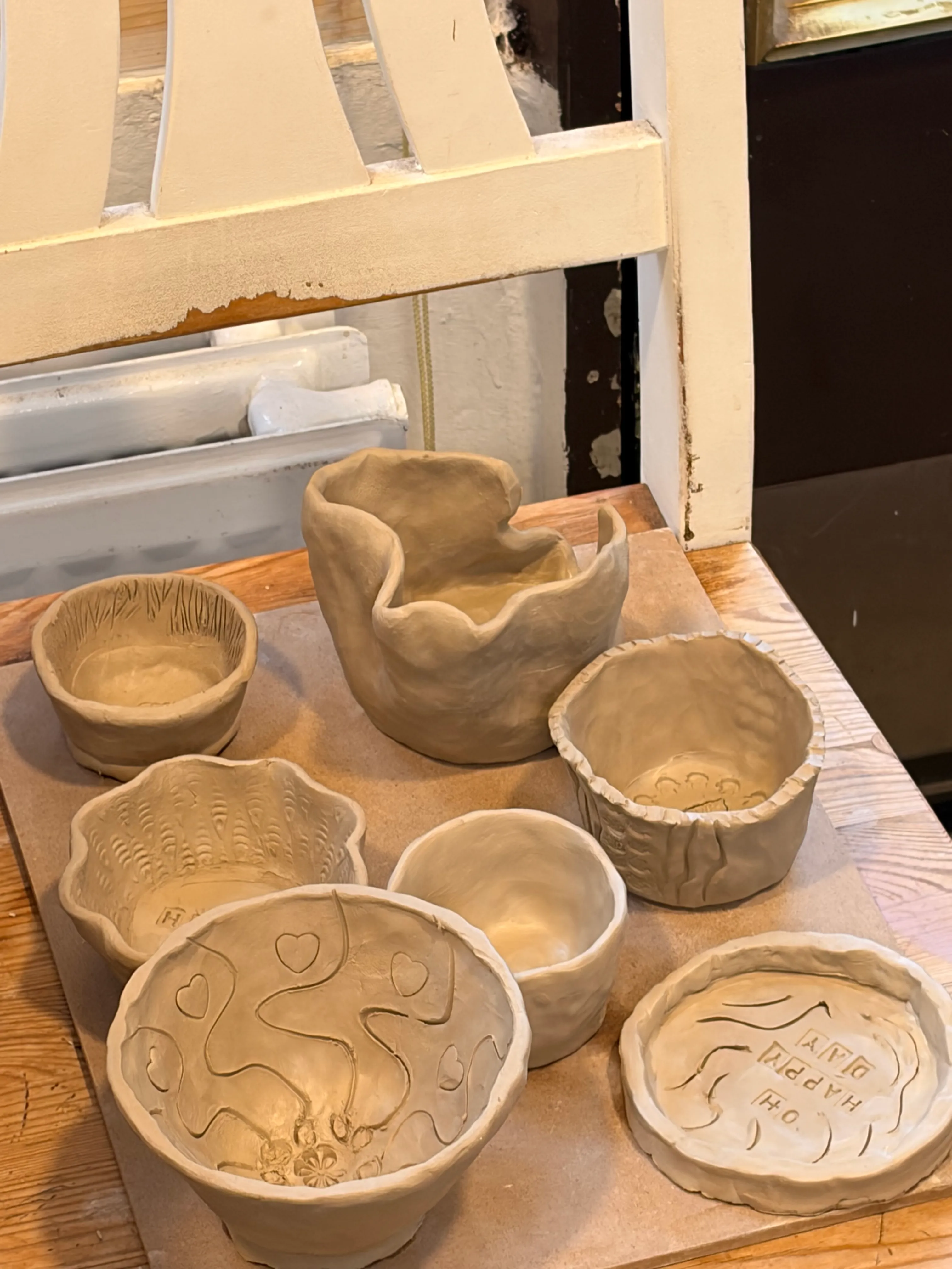 Handgefertigte Ton-Schalen auf einem Holzstuhl.