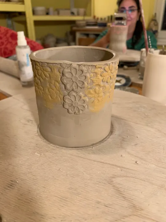 Tontopf mit Blumendesigns auf Holztisch.