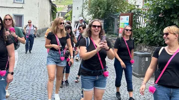 Group of women walking on cobblestone street.