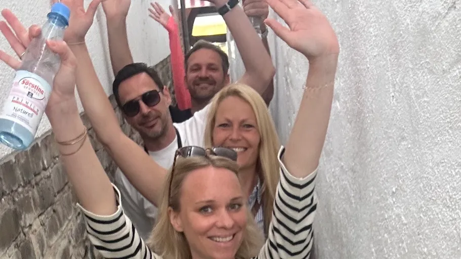 Four people smiling in a narrow alley.