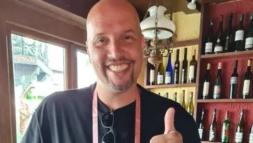 Smiling man giving thumbs up in wine bar.
