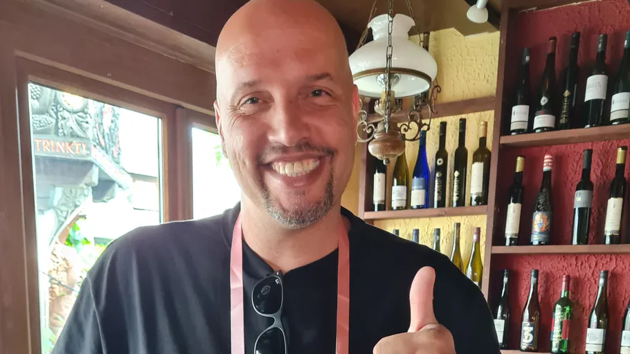 Lächelnder Mann zeigt Daumen hoch in Weinbar.