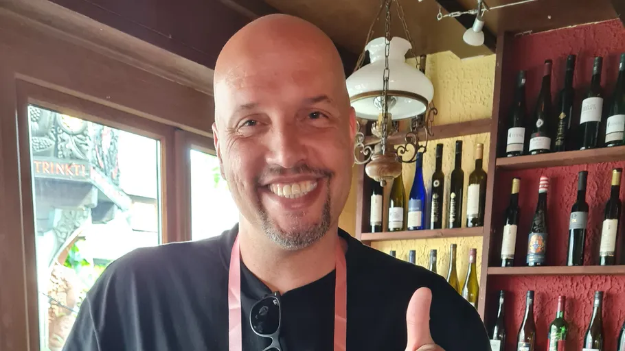 Smiling man giving thumbs up in wine store.