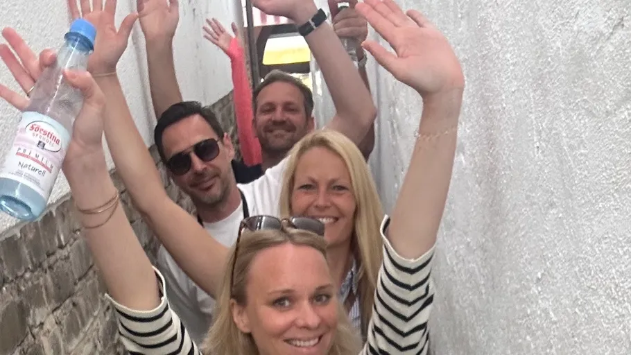 Group of people waving in narrow alley.