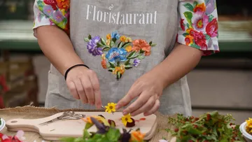 Person arranging flowers on cutting board outdoors.
