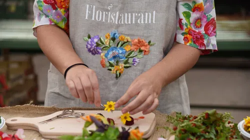 Person arranging flowers on cutting board outdoors.