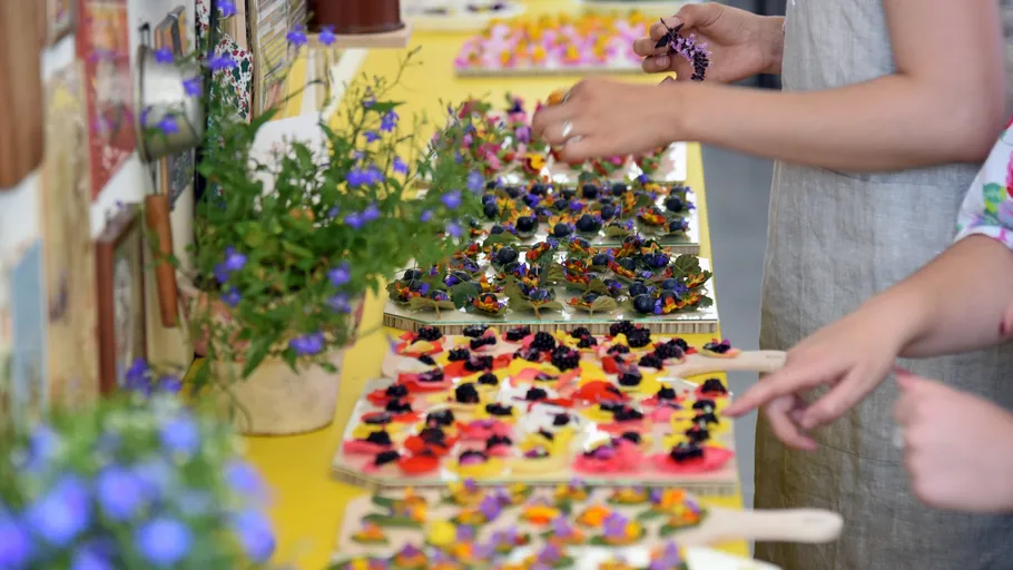 Hands arranging colorful flowers on tiles indoors.