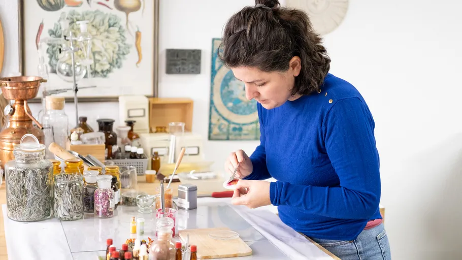 Woman crafting in a workshop with various jars.