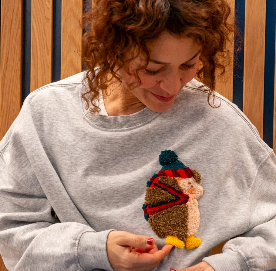 Person trägt Pullover mit Igel-Design drinnen.
