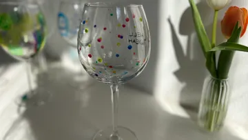 Weingläser mit bunten Punkten auf Tisch.