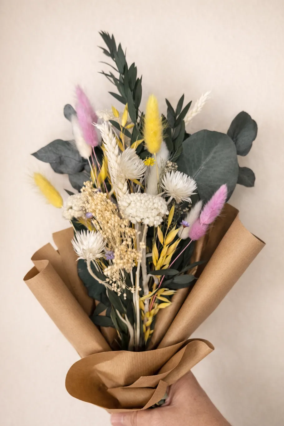 Hand holding bouquet of dried flowers.