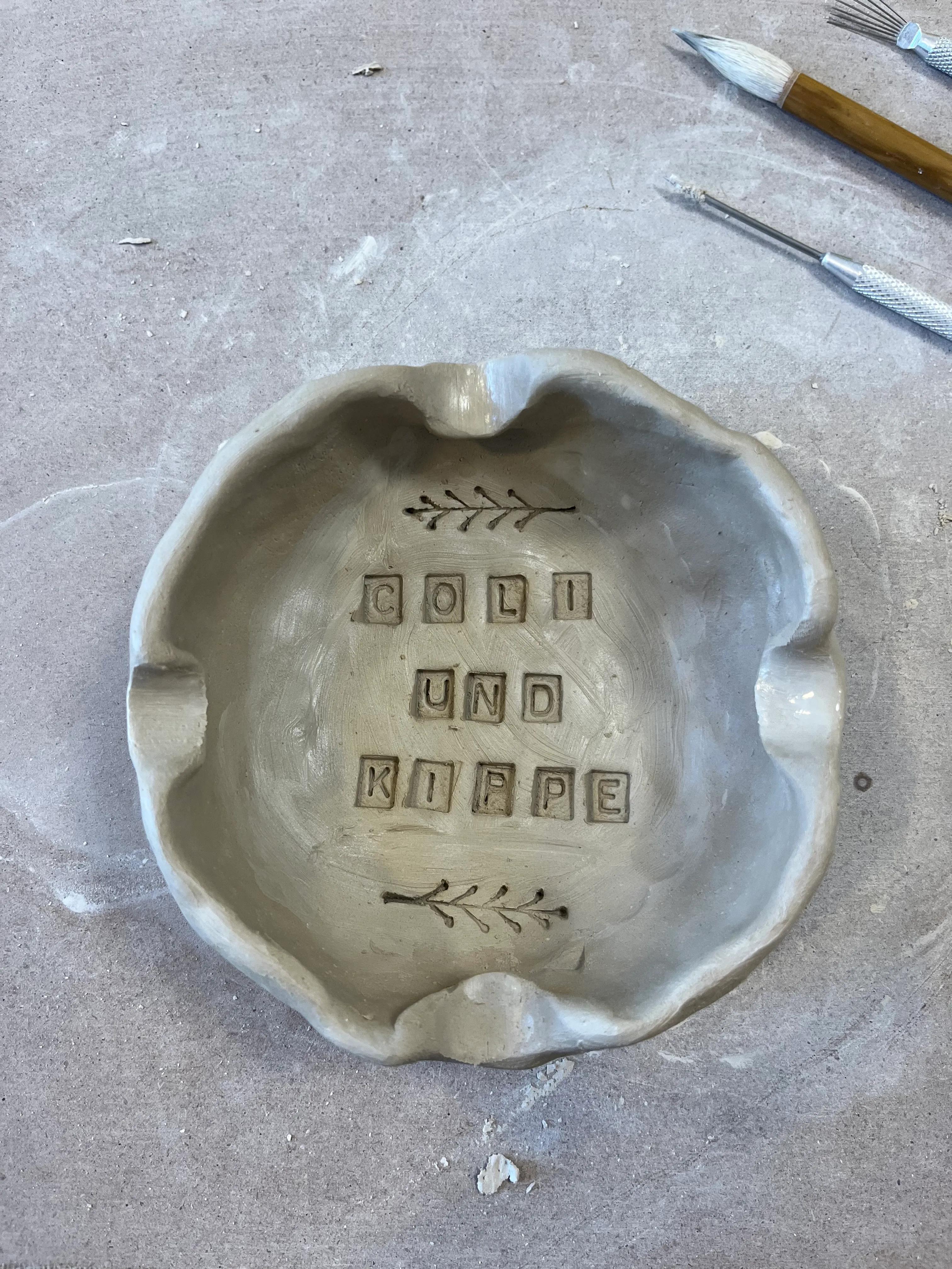 Ton-Schale mit eingraviertem Text auf Tisch.