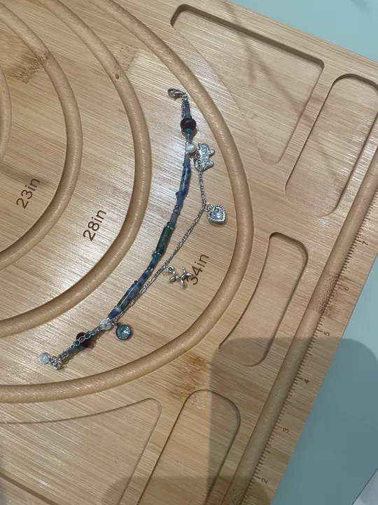 Jewelry on wooden beading board with measurements.