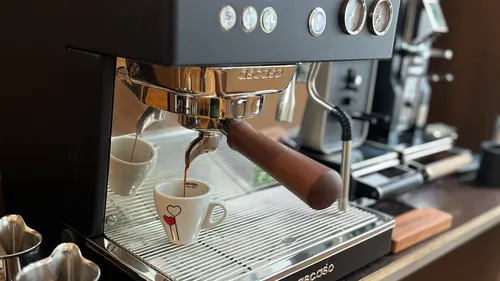 Espresso machine brewing coffee into small cups.