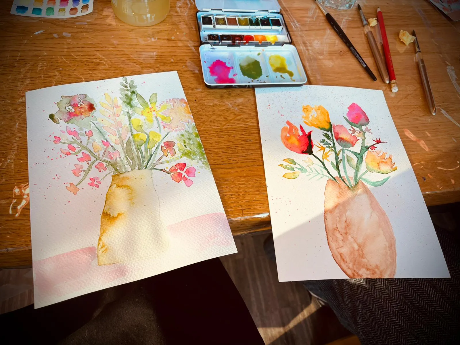 Two watercolor paintings of flower vases on table.