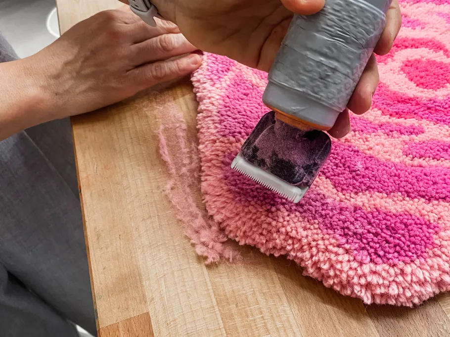Hand using trimmer on colorful rug.