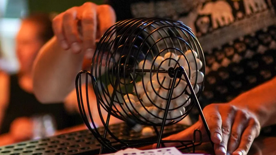 Person turning bingo cage in a game setting.