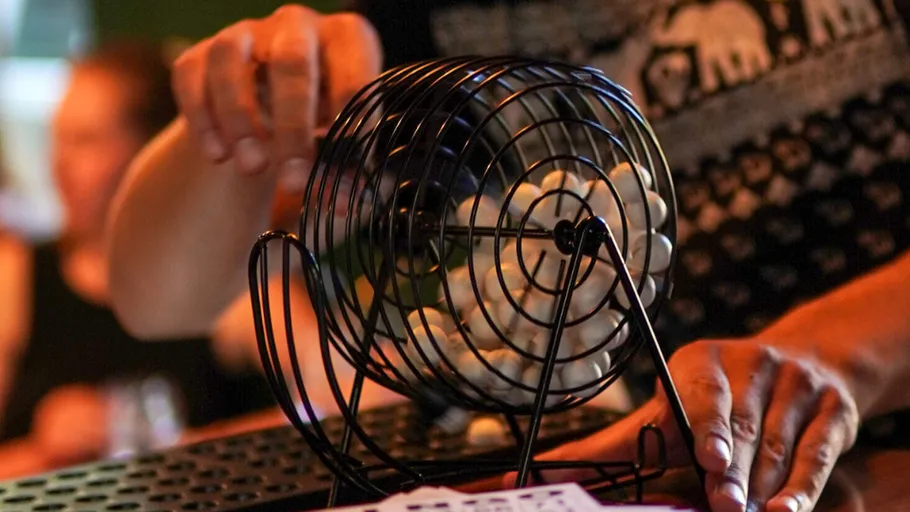 Person turning bingo cage with numbered balls.