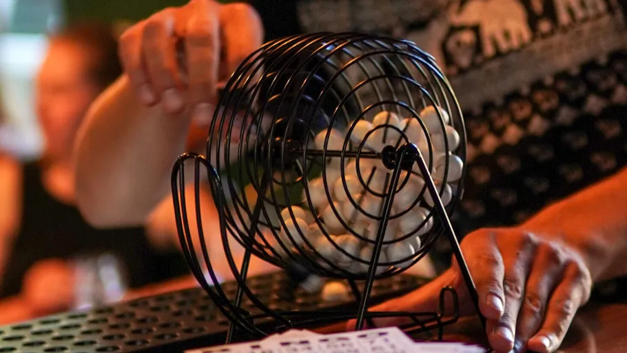 Person turning bingo cage with balls inside.
