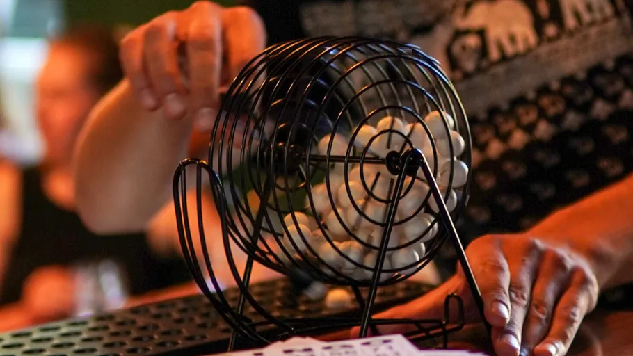 Person spinning bingo cage with balls inside.