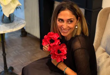 Smiling woman holding red flowers indoors.