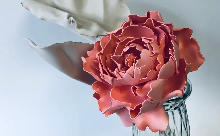 Rosa Blumenskulptur in einer Glasvase.