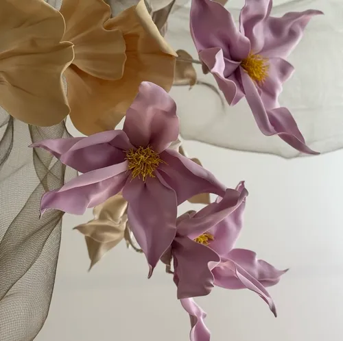 Rosa und beige Blumen vor weichem Stoff.
