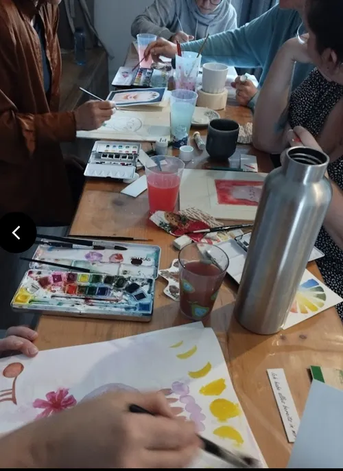 Menschen malen mit Aquarellen an einem Tisch.